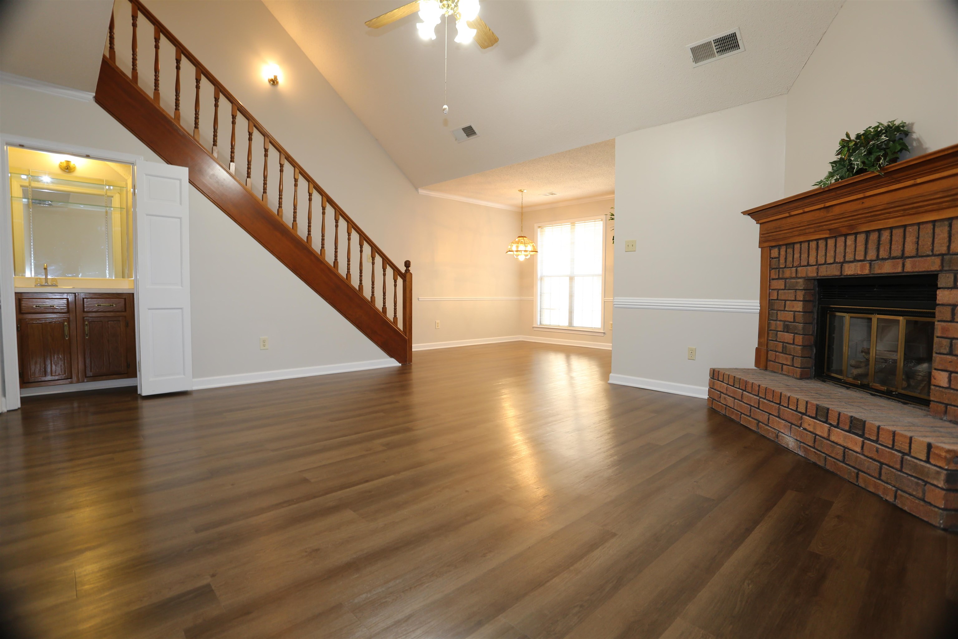 Unfurnished living room featuring ceiling fan with notable chandelier, high vaulted ceiling, dark hardwood / wood-style flooring, and a fireplace