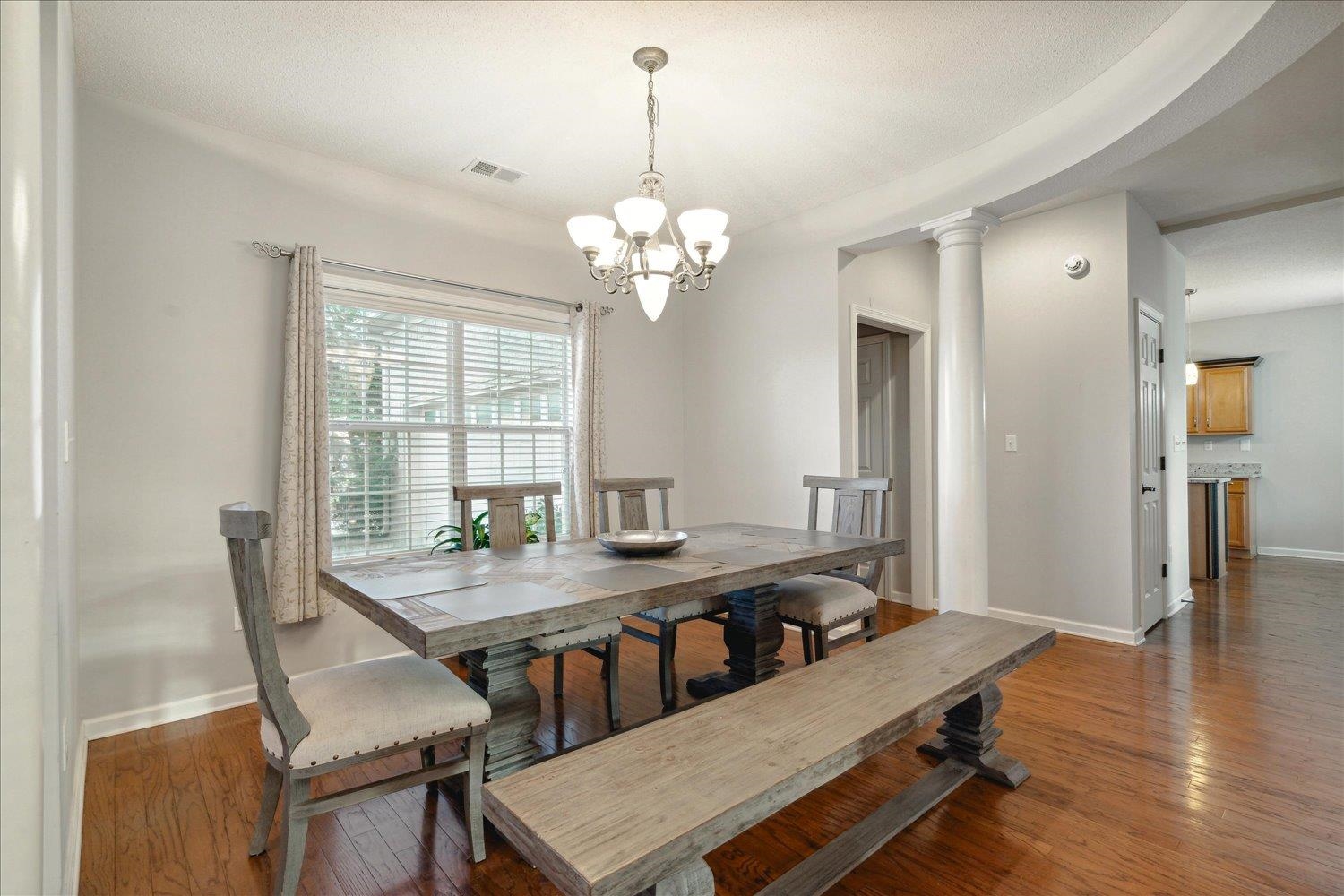 Dining room featuring a chandelier, dark wood-type flooring, and ornate columns