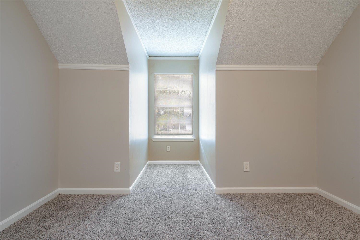 Interior space with lofted ceiling, a textured ceiling, and ornamental molding