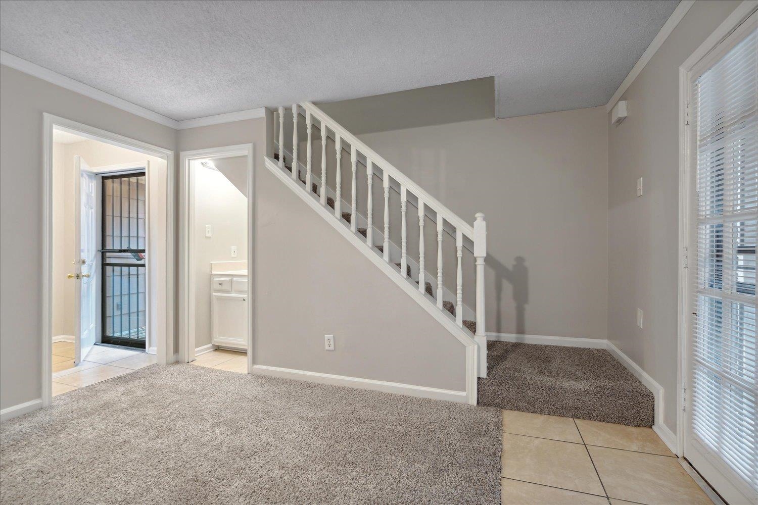 Stairs featuring carpet, a textured ceiling, and ornamental molding