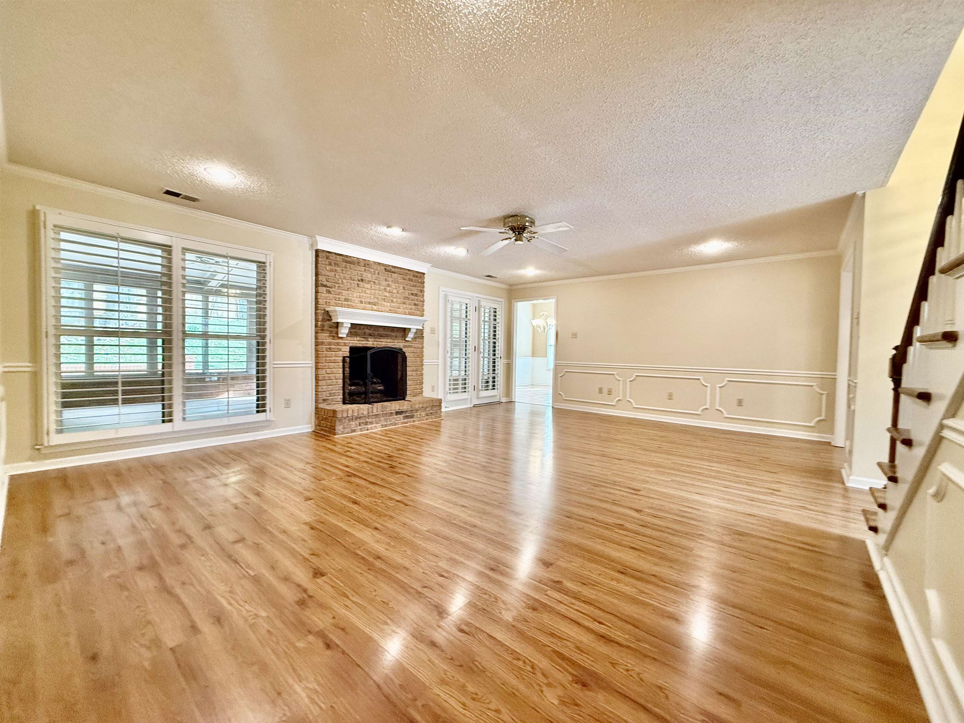 Great Room with light hardwood / wood-style flooring, a brick fireplace, a textured ceiling, and a healthy amount of sunlight