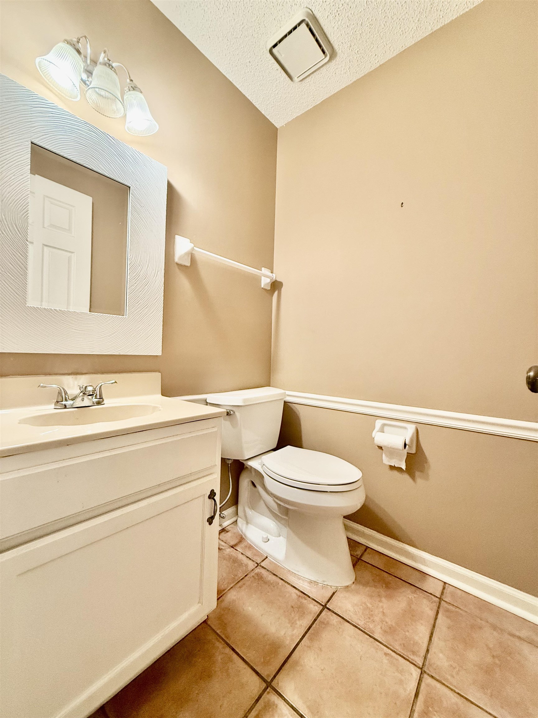 Bathroom with toilet, a textured ceiling, vanity, and tile patterned floors