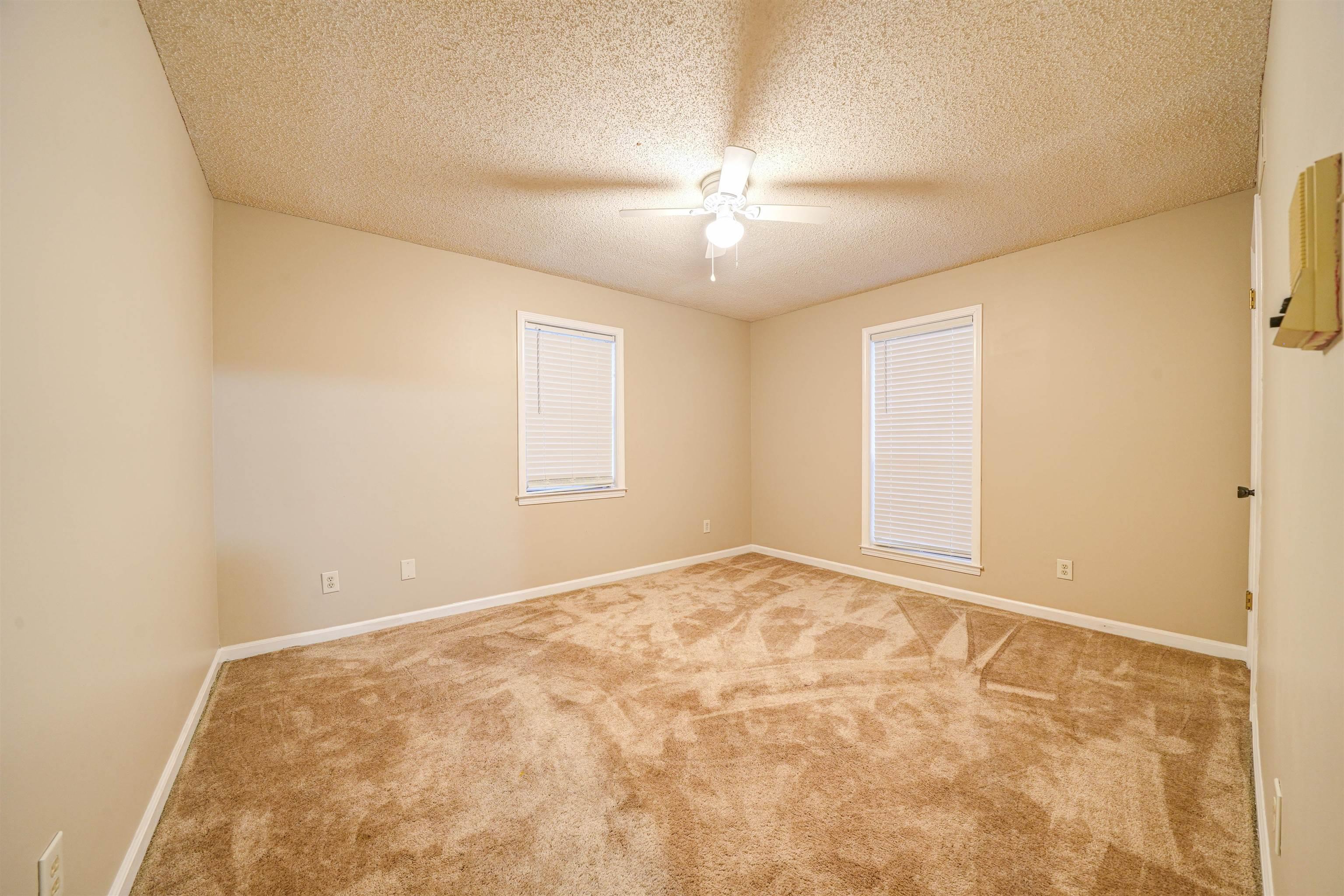 Carpeted empty room with ceiling fan and a textured ceiling