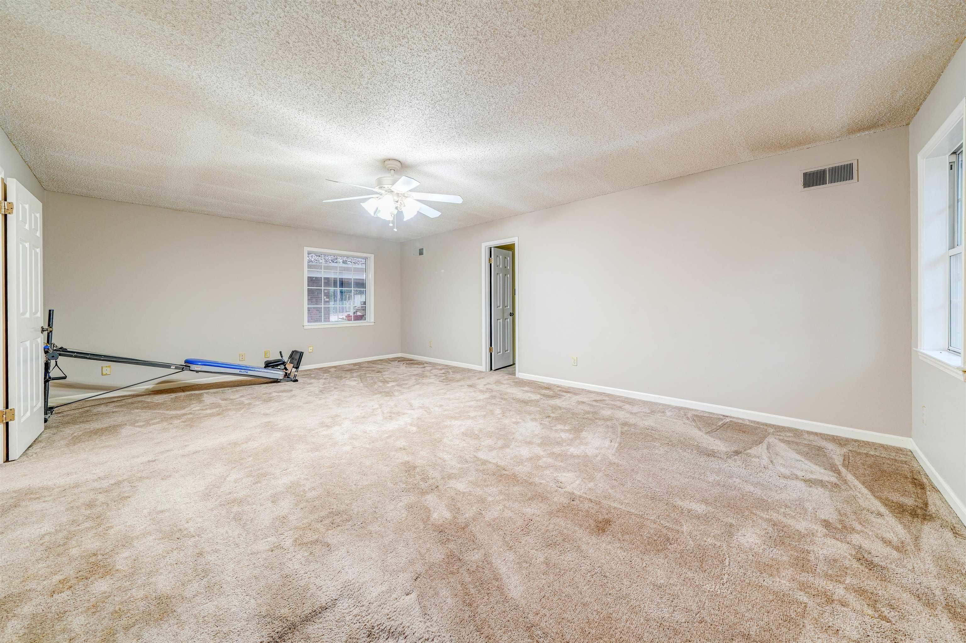 Unfurnished room featuring a textured ceiling, carpet flooring, and ceiling fan