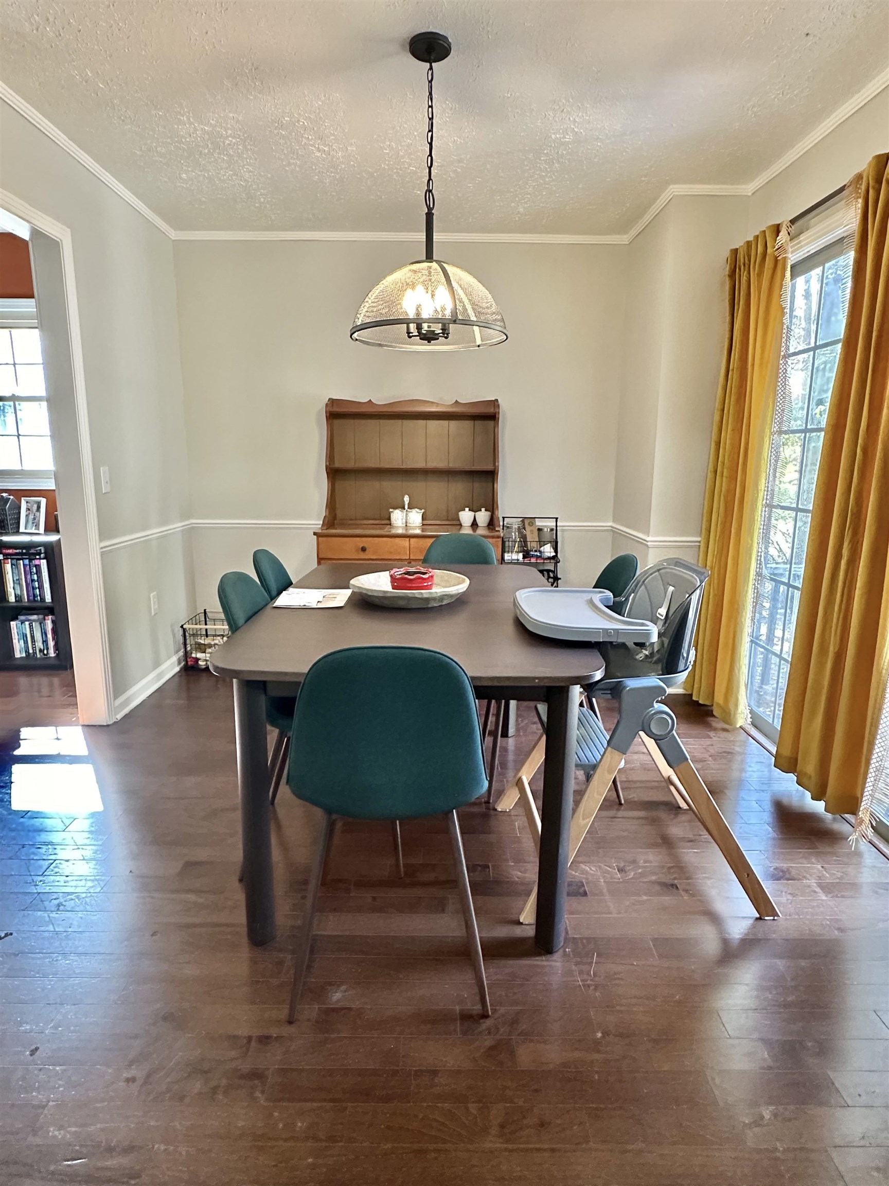 Dining space featuring ornamental molding, a notable chandelier, a textured ceiling, and dark wood-type flooring