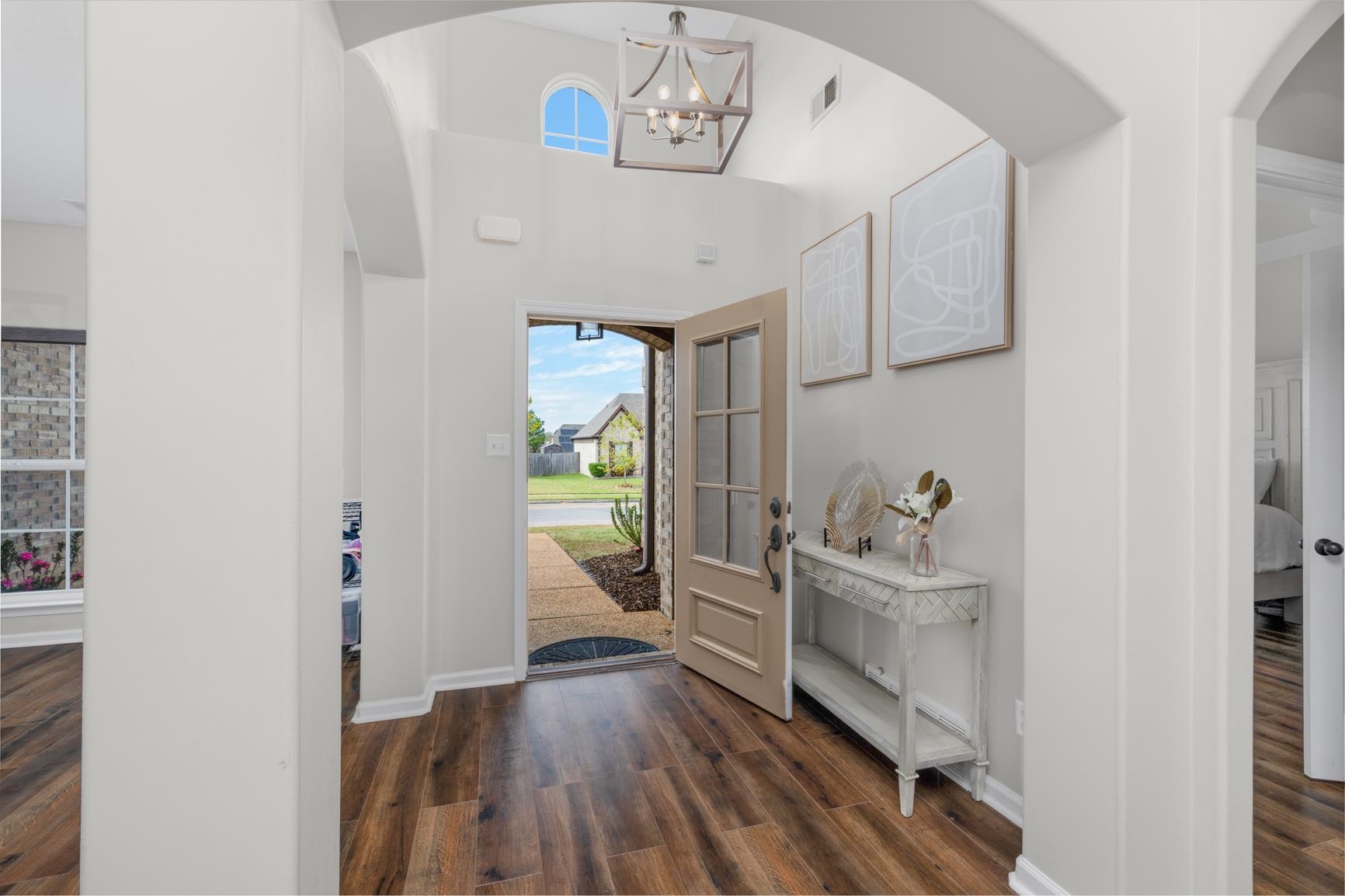 Foyer entrance with dark wood-type flooring, a towering ceiling, and an inviting chandelier