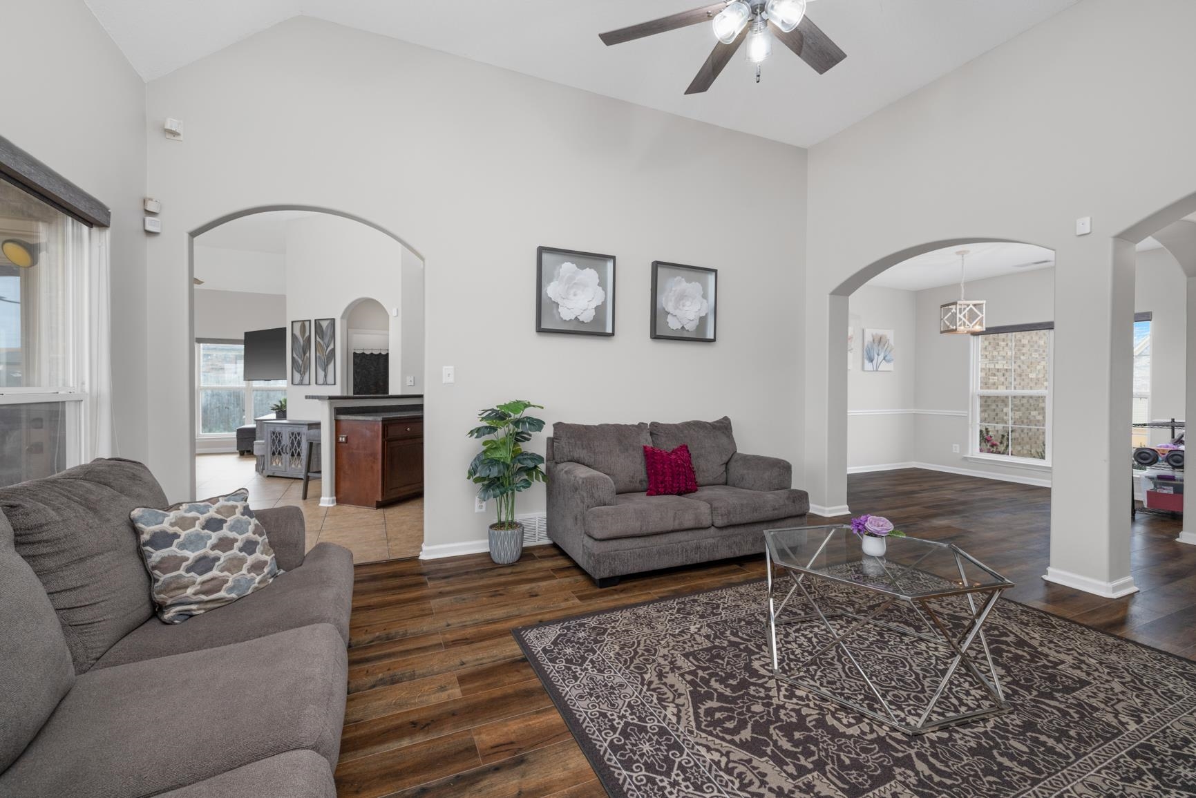 Living room with a healthy amount of sunlight, high vaulted ceiling, and dark wood-type flooring