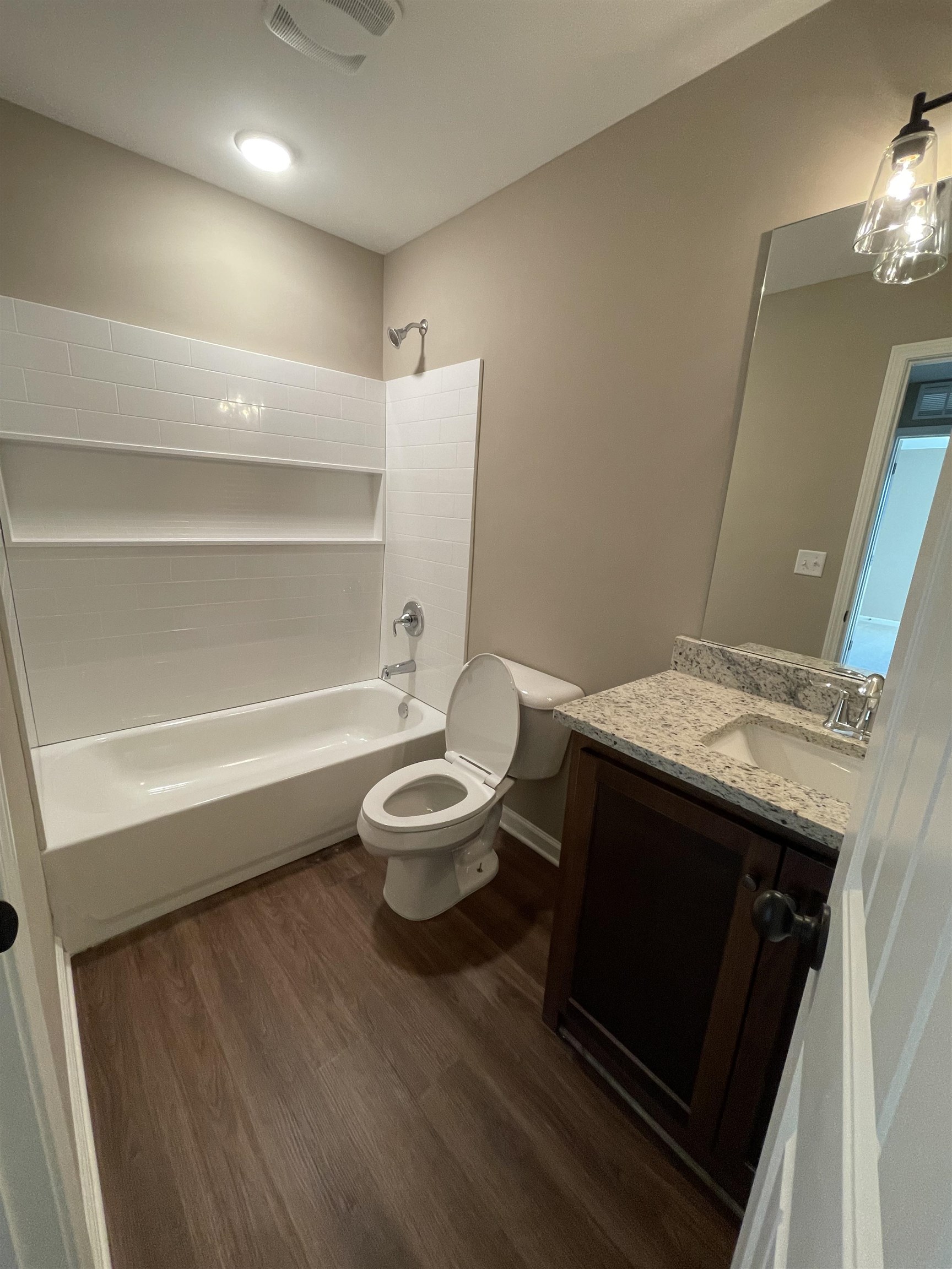 Full bathroom featuring hardwood / wood-style floors, vanity, toilet, and bathtub / shower combination