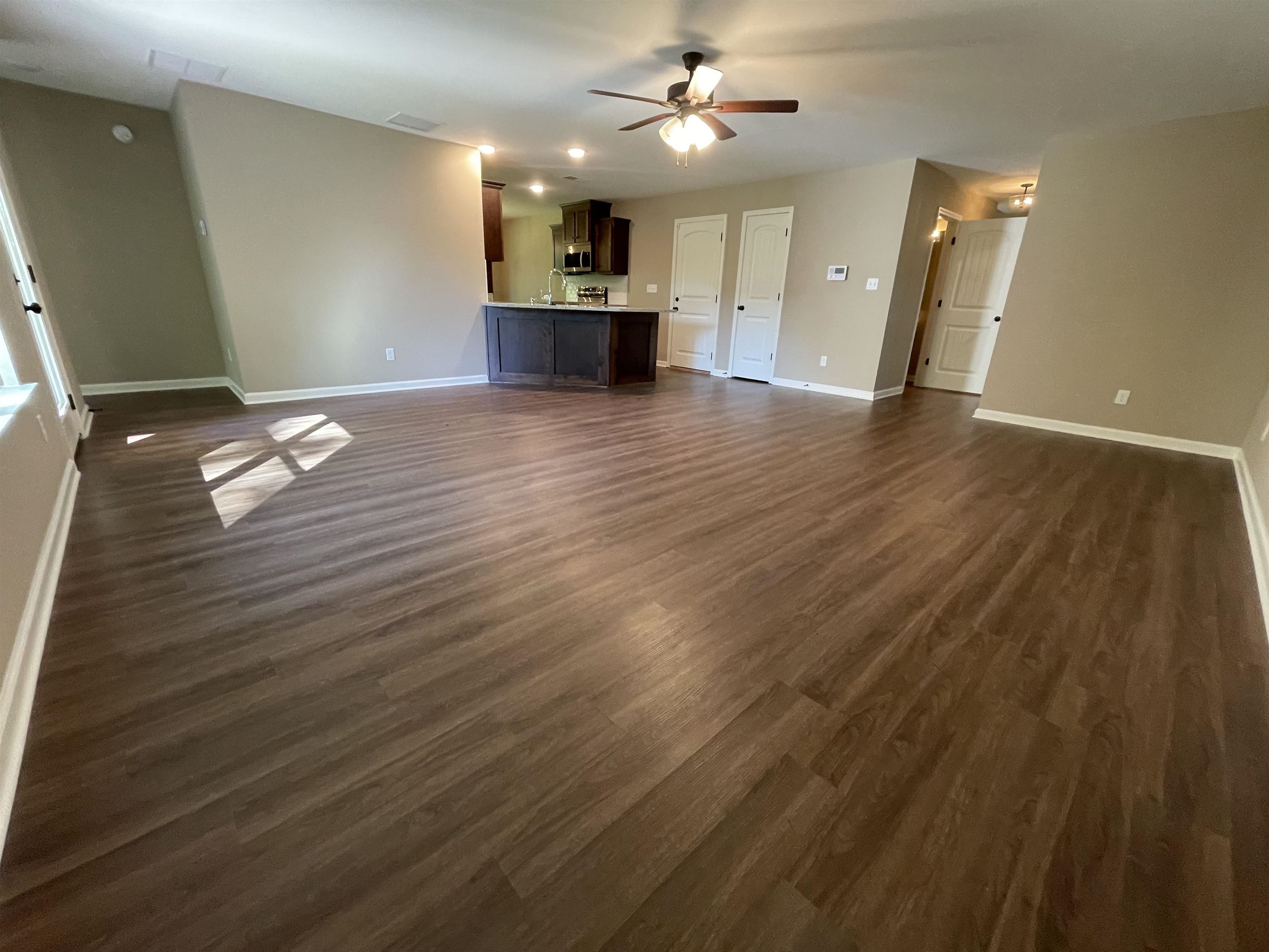 Unfurnished living room with dark hardwood / wood-style flooring, ceiling fan, and sink