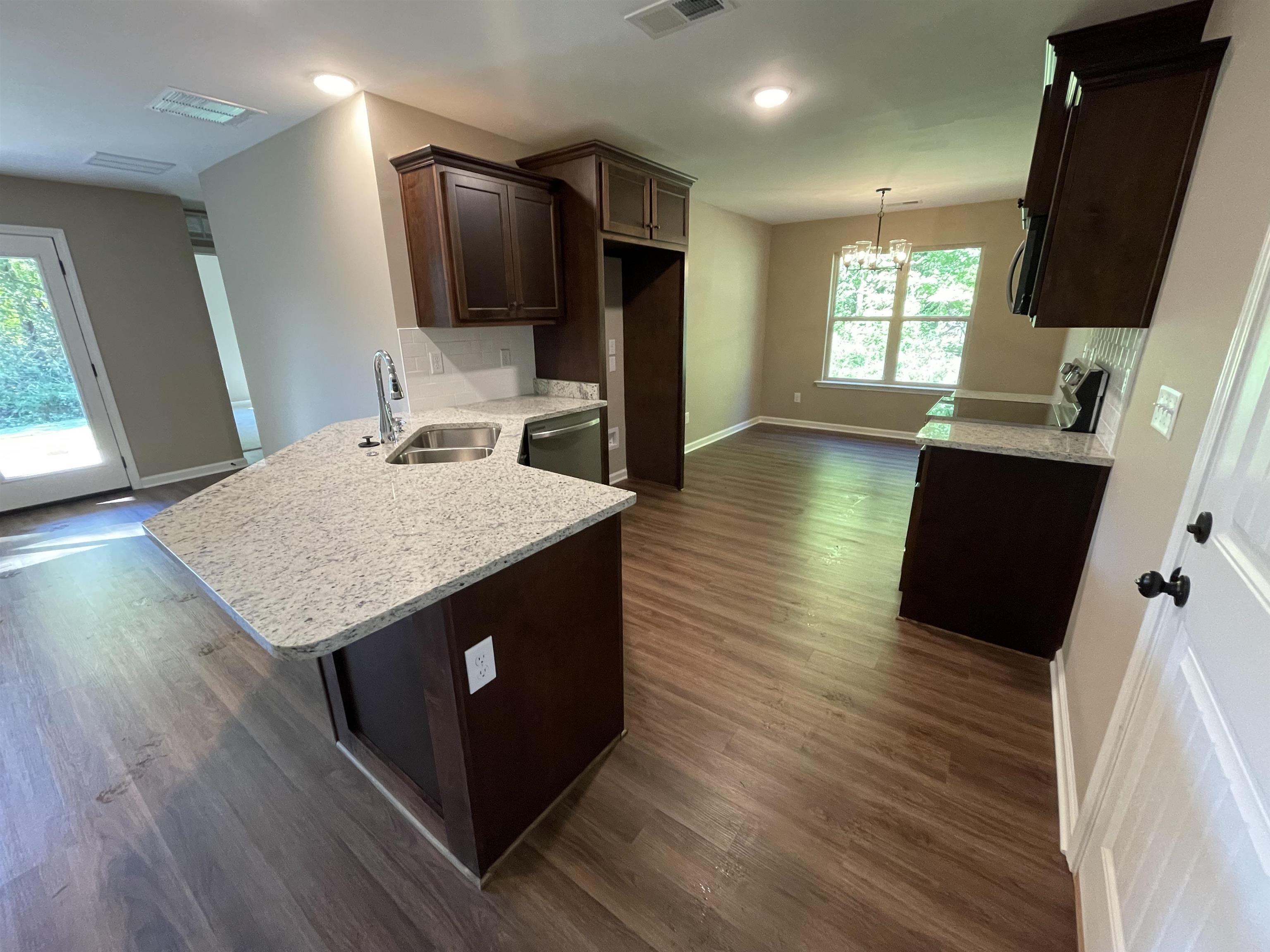 Kitchen with stainless steel dishwasher, hanging light fixtures, sink, and dark hardwood / wood-style floors