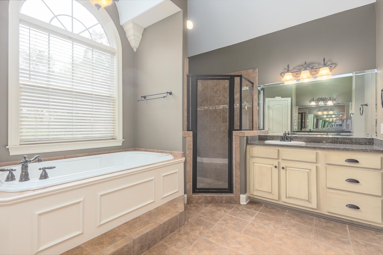 Bathroom with a wealth of natural light, independent shower and bath, and vanity