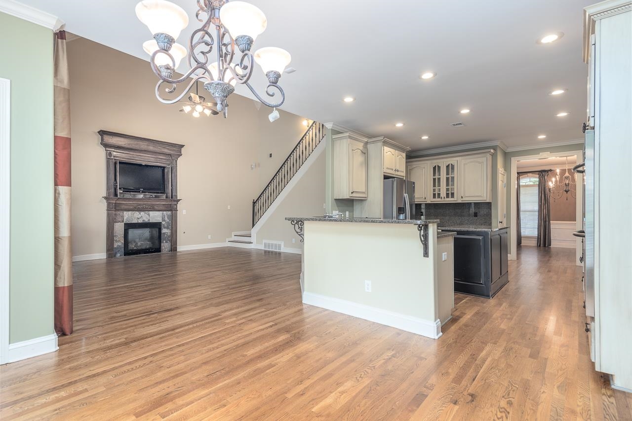 Kitchen with crown molding, stainless steel fridge with ice dispenser, cream cabinetry, and light hardwood / wood-style floors