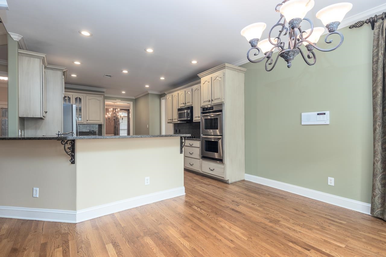 Kitchen featuring decorative backsplash, ornamental molding, stainless steel appliances, and light wood-type flooring