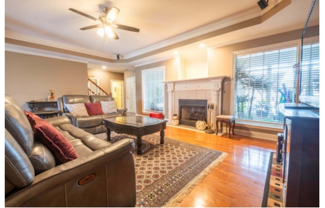 Living room with a tiled fireplace, light hardwood / wood-style floors, crown molding, and a tray ceiling