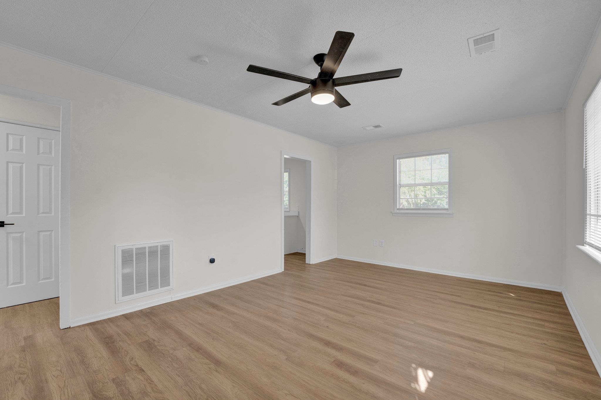 Empty room featuring light wood-type flooring, a textured ceiling, and ceiling fan