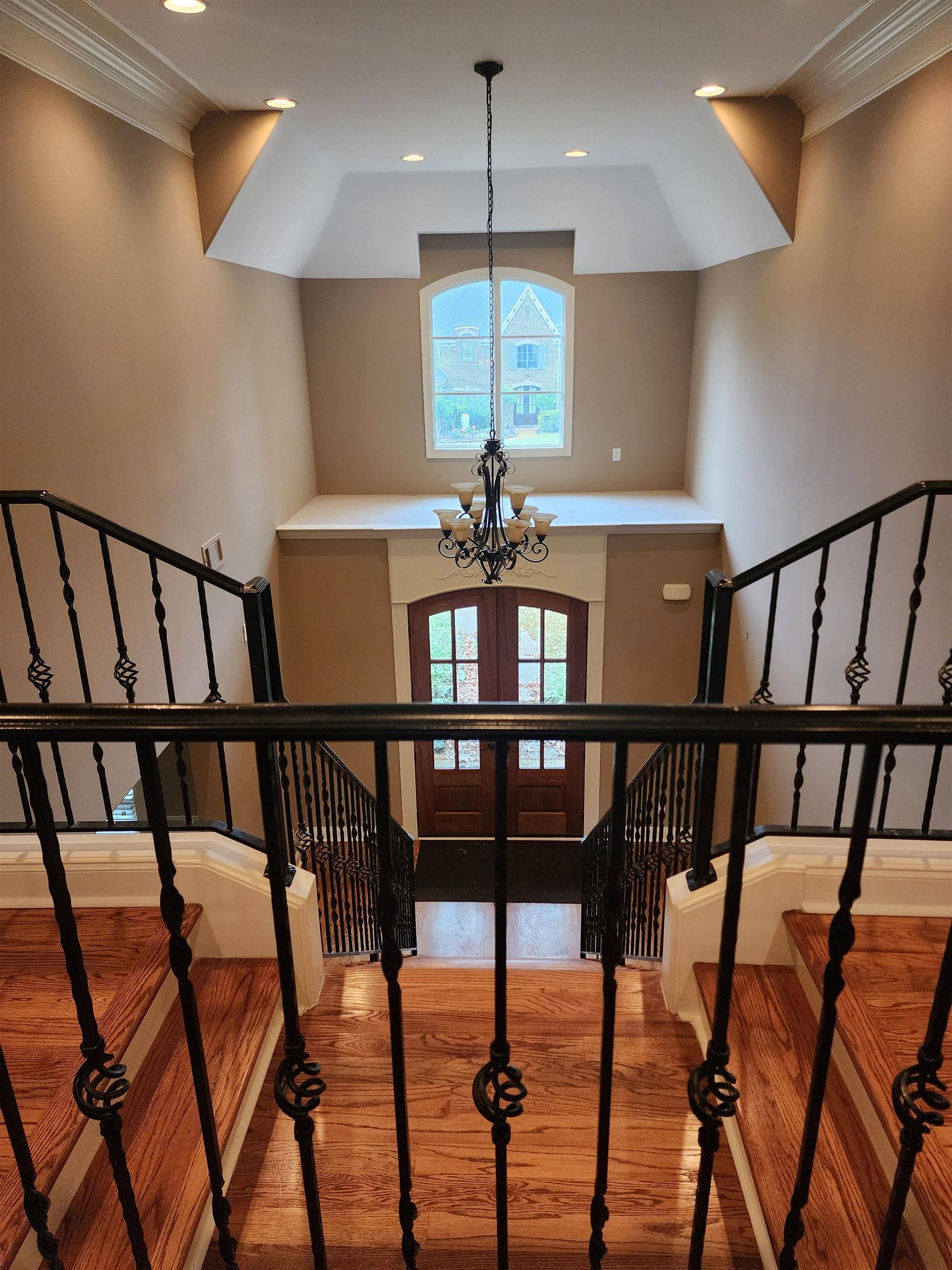 Staircase with an inviting chandelier, crown molding, and wood-type flooring