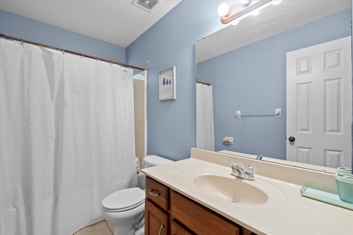 Bathroom featuring curtained shower, tile patterned floors, vanity, and toilet