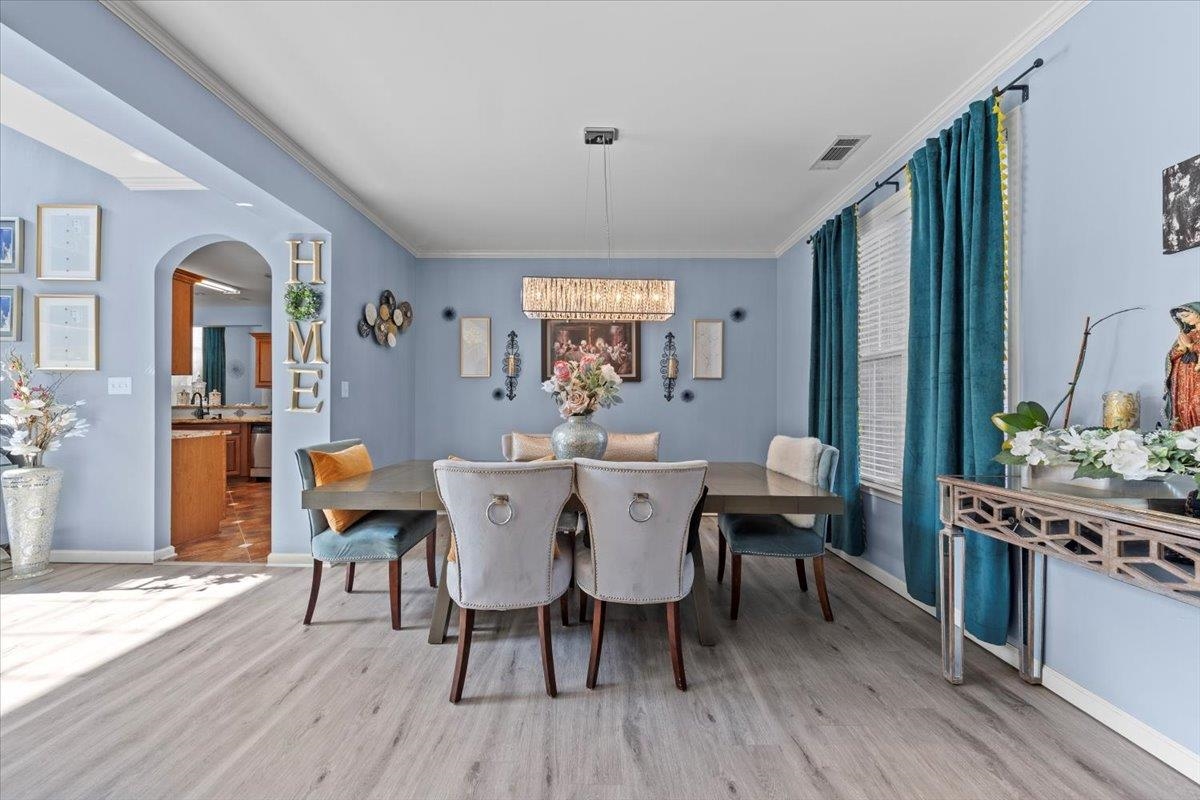 Dining room with a notable chandelier, light hardwood / wood-style flooring, and ornamental molding