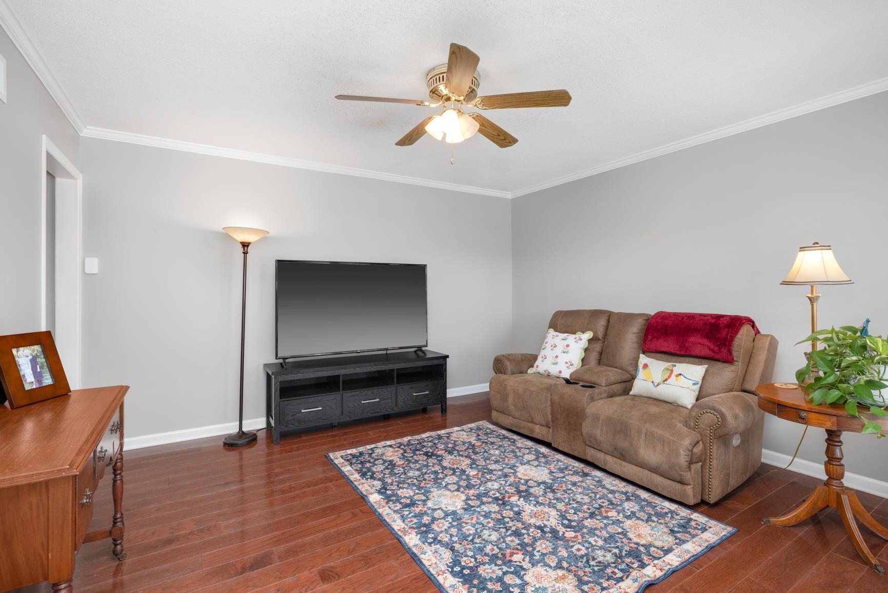 Living room with ceiling fan, dark hardwood / wood-style flooring, and ornamental molding. Freshly Painted Interior.