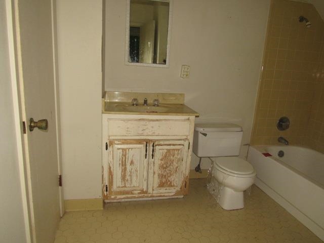 Full bathroom featuring tile patterned flooring, vanity, tiled shower / bath combo, and toilet