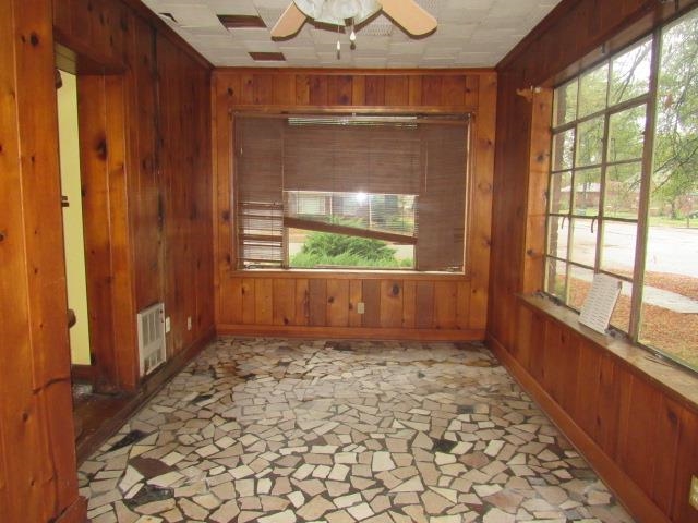 Unfurnished sunroom with a wealth of natural light and ceiling fan