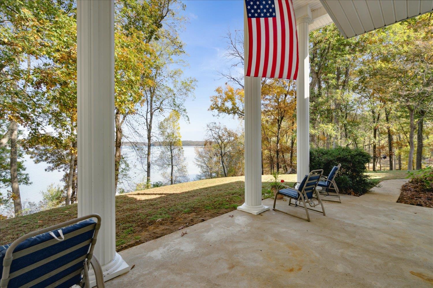 Nestled among sprawling oaks & bright yellow hickory trees, this home comes w/ 37 acres of unrestricted land & approximately 1,500 feet of waterfront access. You will fall in love w/ this custom built Antebellum style home overlooking Kentucky Lake. Enjoy your coffee from the 2nd floor balcony while you watch the Tennessee River come to life. The property already has its own concrete boat ramp & dock. The decking was replaced in 2023. In addition to the main home which boasts 3884 S/F, there is a 3 car carriage house w/ a bath & central HVAC. Large 5 stall boat & equipment shed. Finally, there is a workshop included. The home is supplied w/ fresh spring water which remains at a constant 50 degrees, year round. Indoor filtration system ensures the best quality water that you will never pay for while you live here. This land is zoned green belt for timber.  You will find numerous trails on the property to ride your ATV.  Land would be perfect to build tiny homes for short term rentals.