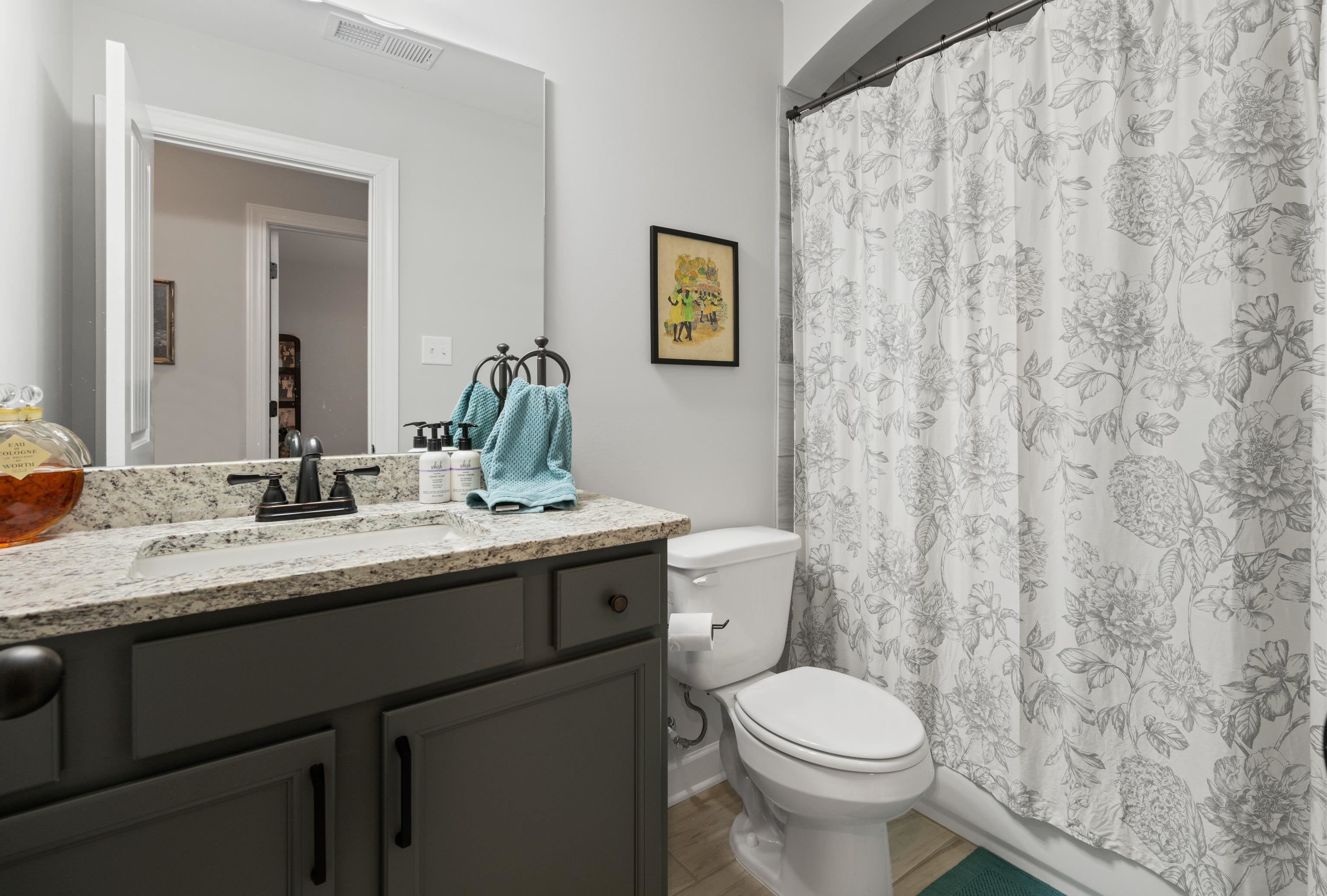 Full bathroom with vanity, hardwood / wood-style flooring, toilet, and shower / tub combo