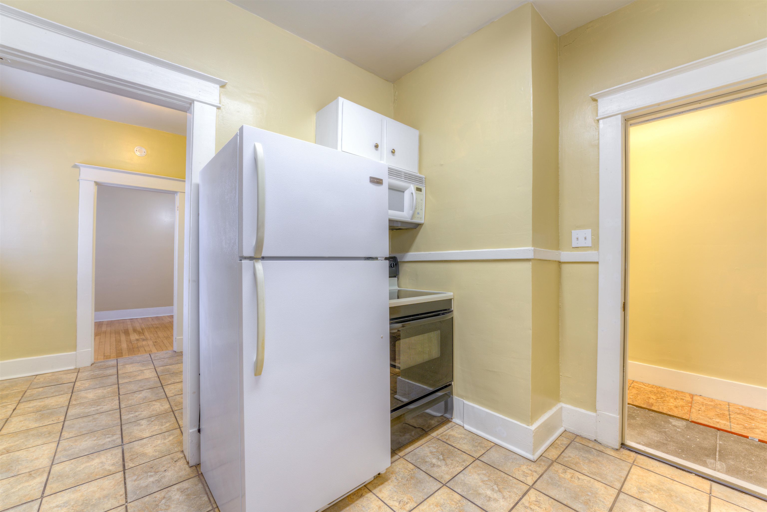 Kitchen with white cabinetry, light tile patterned floors, and white appliances