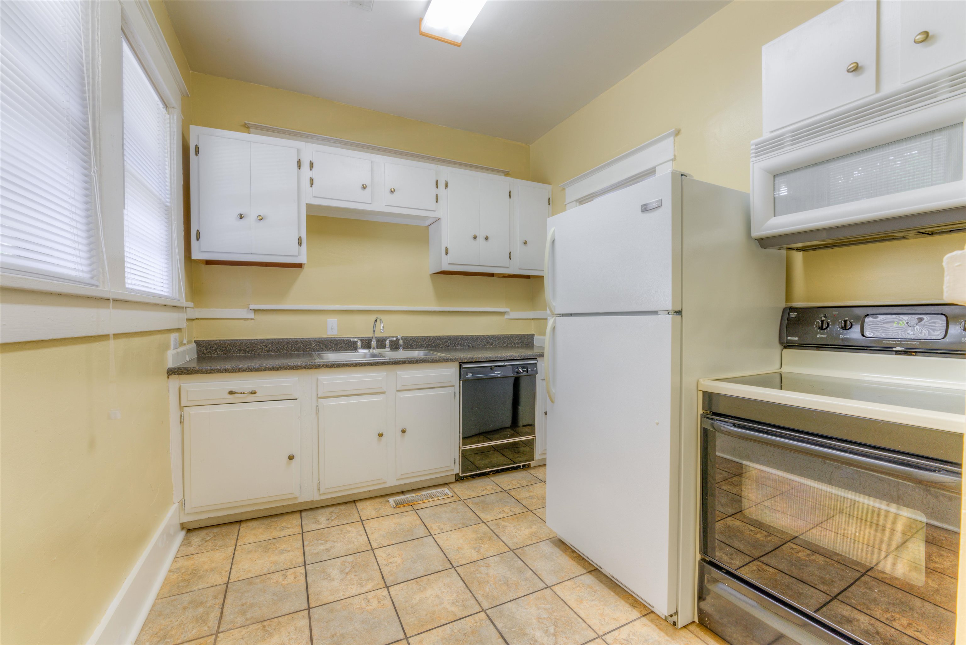 Kitchen featuring white cabinetry, white appliances, sink, and light tile patterned flooring