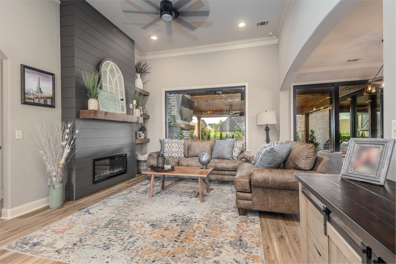 Living room featuring crown molding, a large fireplace, and light hardwood / wood-style flooring