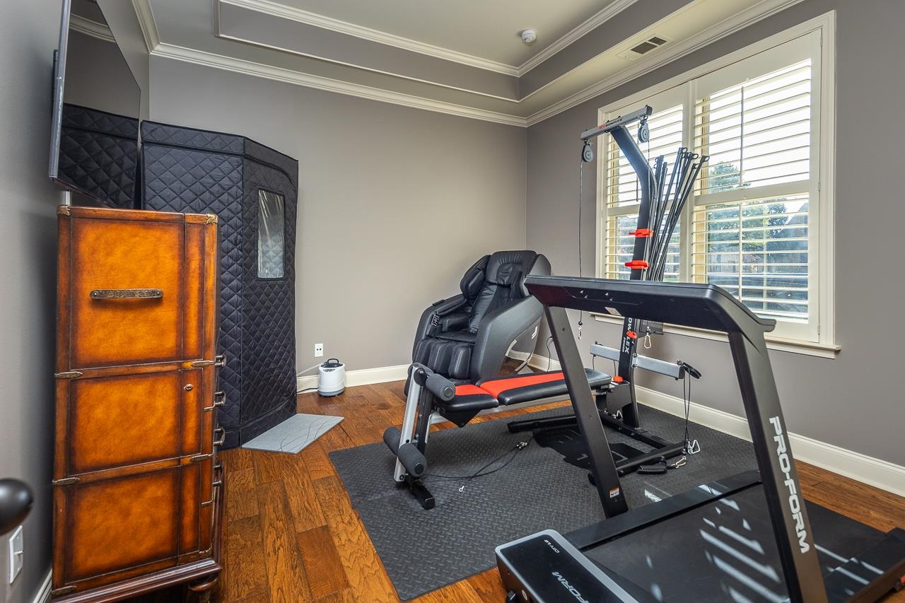 Exercise area with dark hardwood / wood-style flooring and crown molding