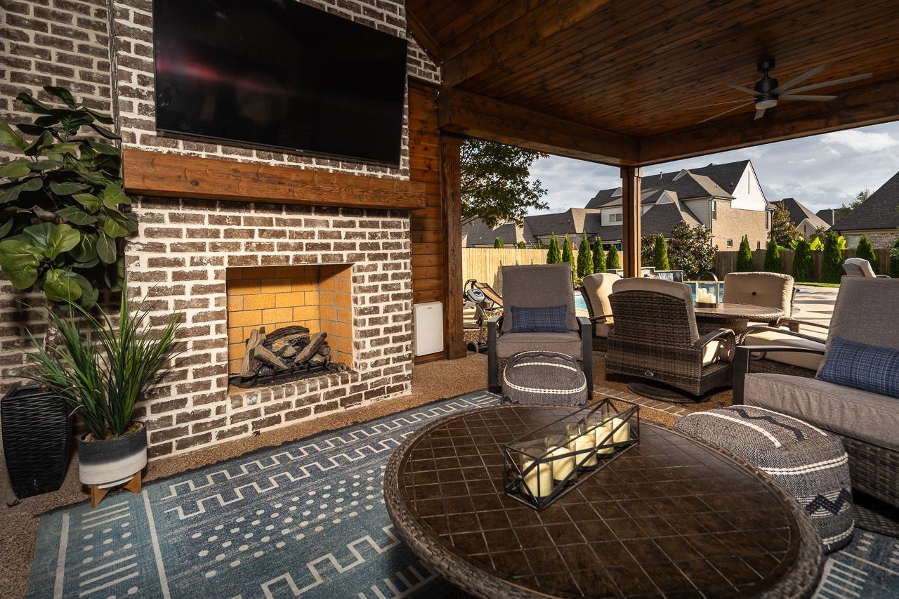 View of patio featuring an outdoor brick fireplace and ceiling fan