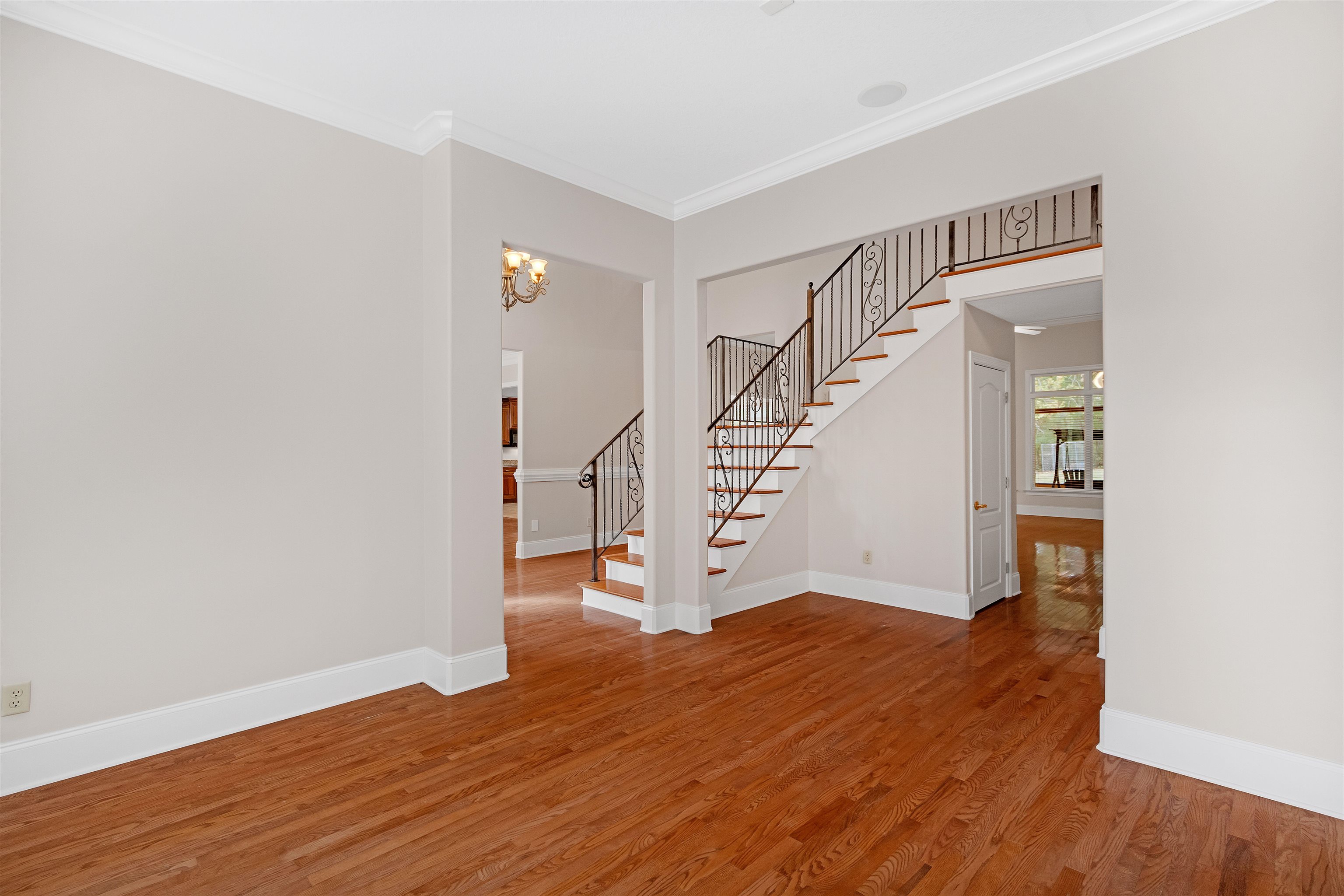 Interior space featuring ornamental molding, wood-type flooring, and a chandelier