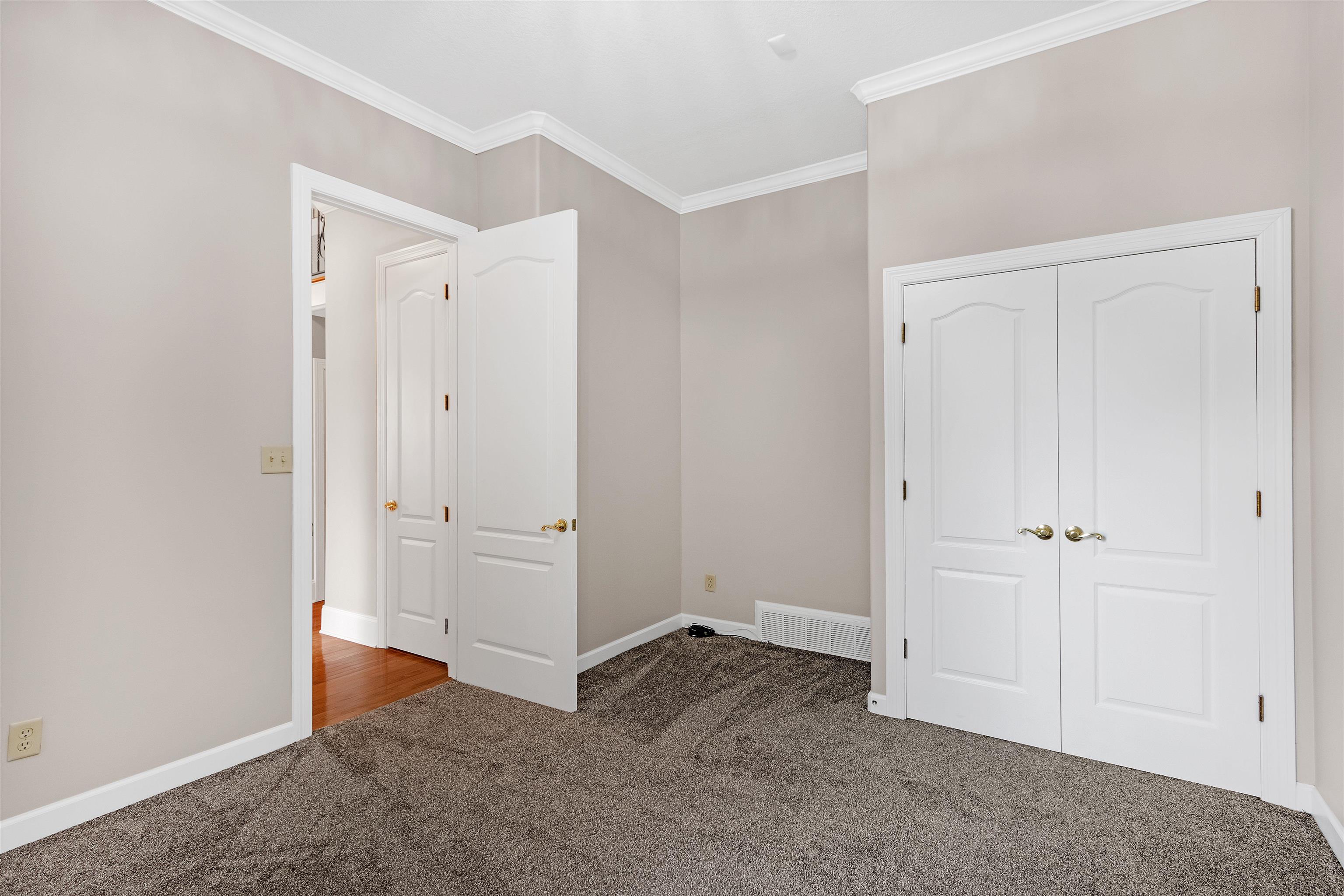 Unfurnished bedroom featuring a closet, carpet floors, and ornamental molding