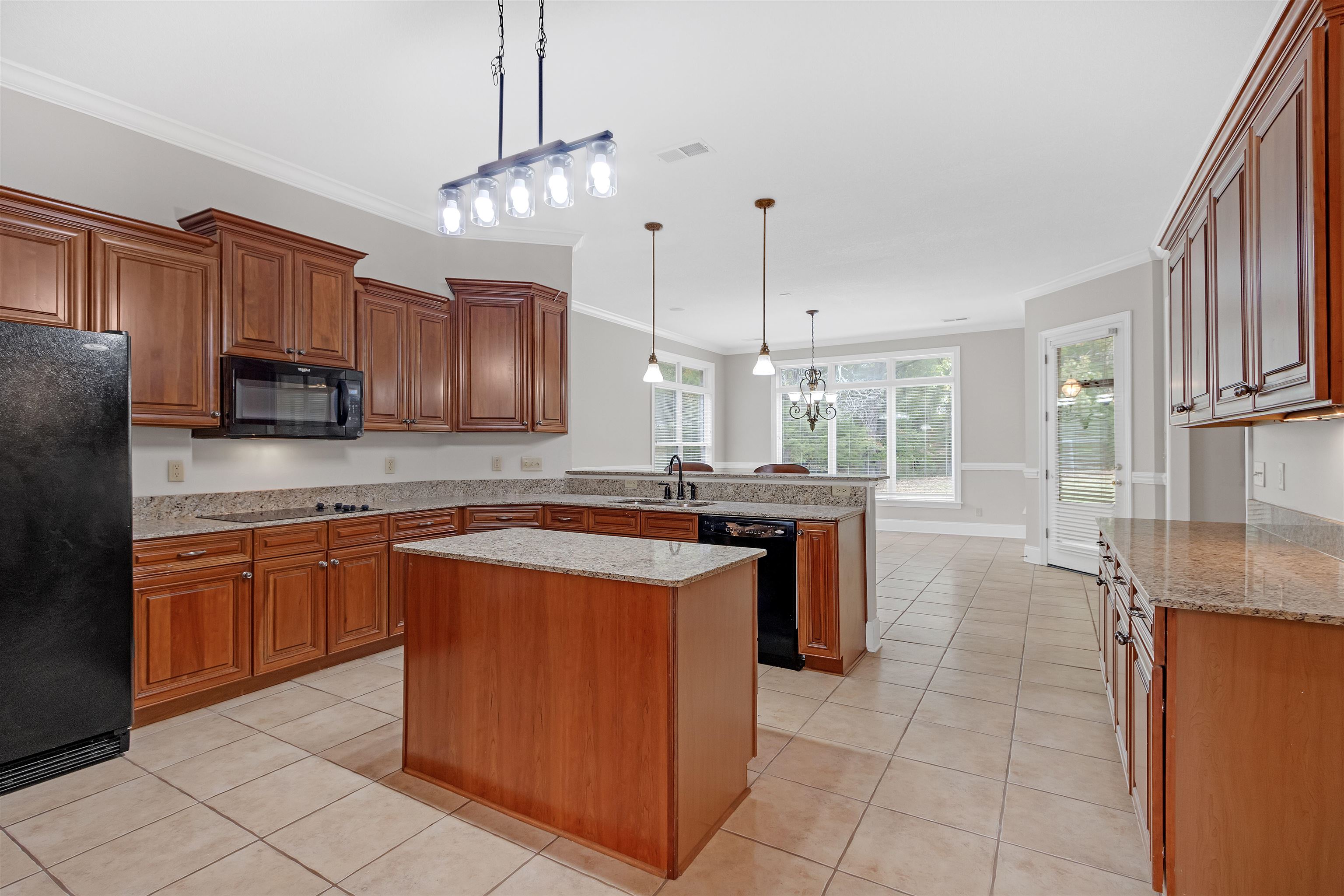 Kitchen featuring a center island, kitchen peninsula, black appliances, sink, and decorative light fixtures