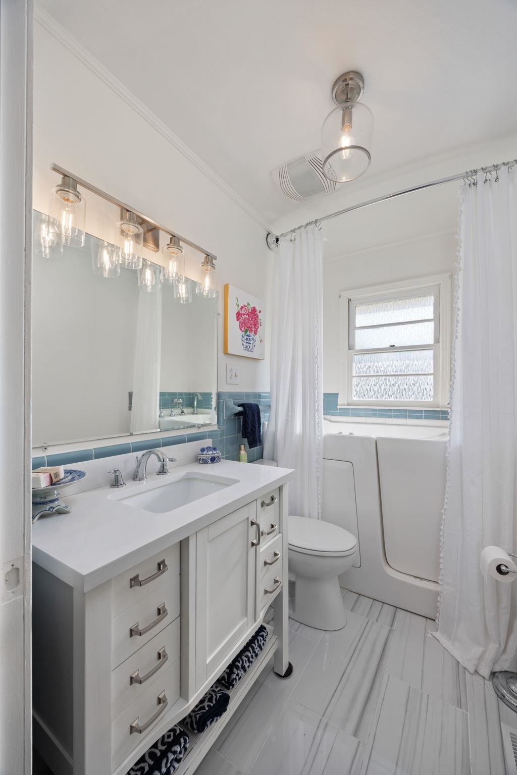 Full bathroom with ornamental molding, vanity, toilet, and shower / tub combo with curtain