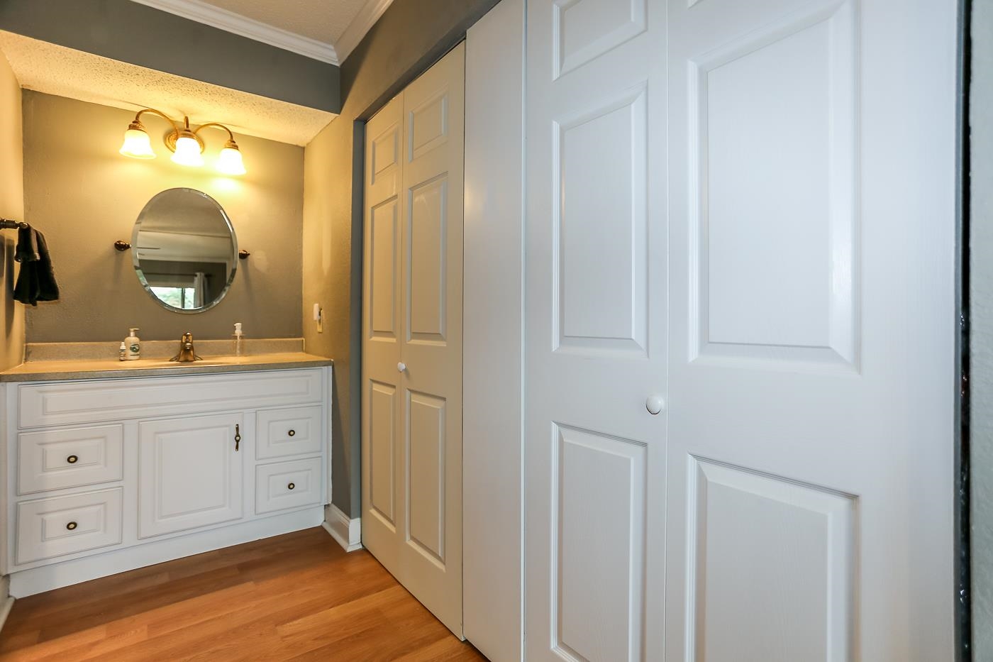 Bathroom with a textured ceiling, vanity, hardwood / wood-style floors, and crown molding