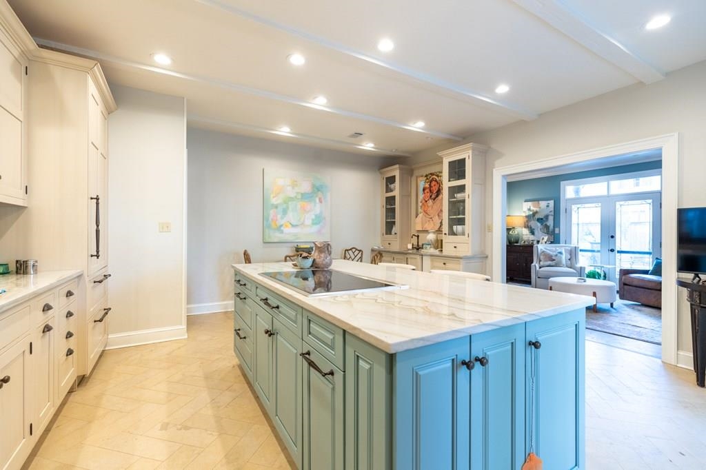 Kitchen with french doors, black electric cooktop, light stone counters, beamed ceiling, and a kitchen island