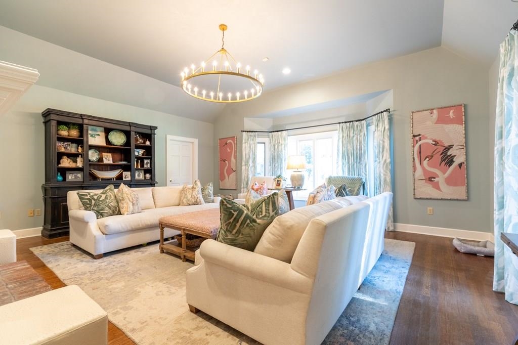 Living room with hardwood / wood-style flooring, a chandelier, and vaulted ceiling