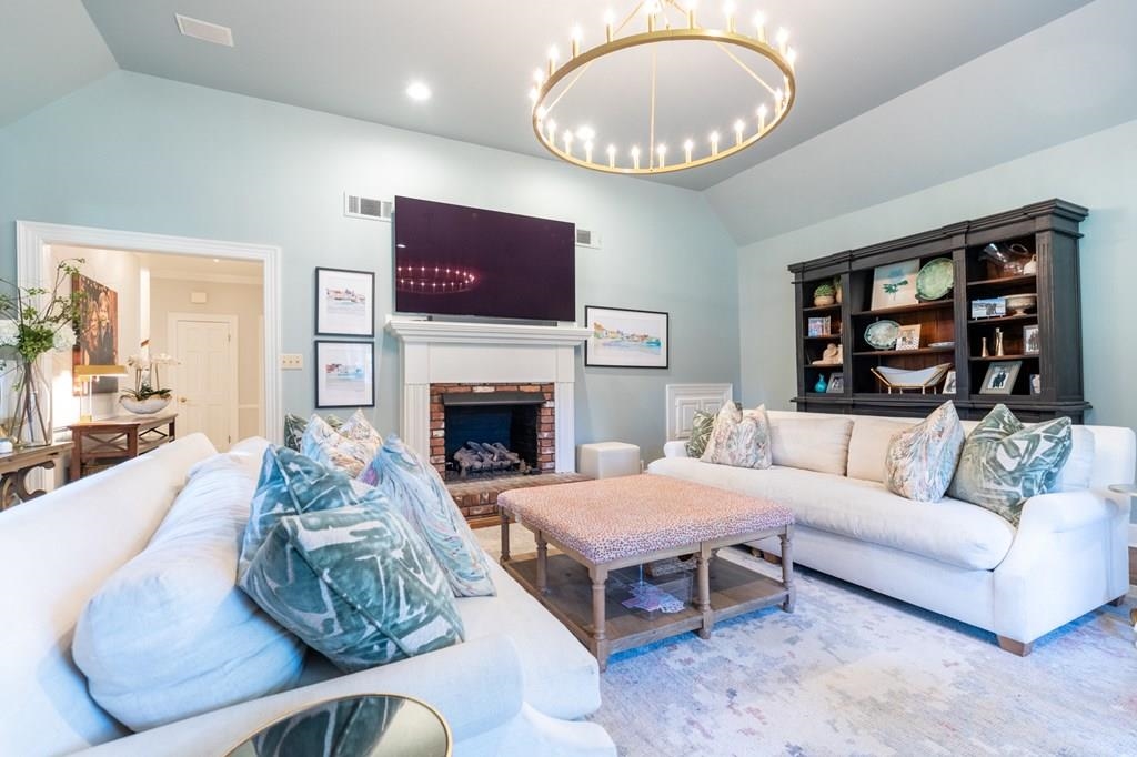 Living room featuring a fireplace, lofted ceiling, and a chandelier