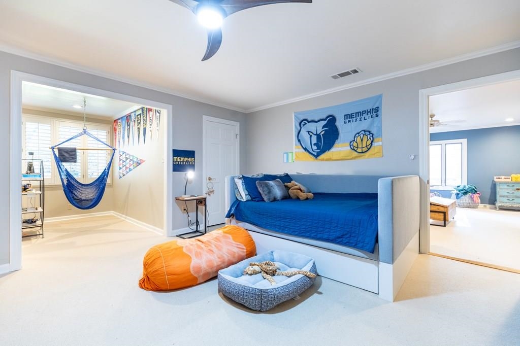 Bedroom featuring ceiling fan, carpet flooring, and ornamental molding