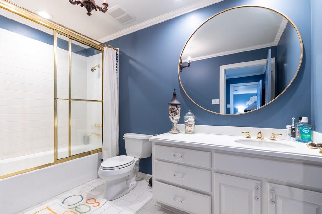 Full bathroom featuring tile patterned floors, ornamental molding, vanity, shower / tub combo, and toilet