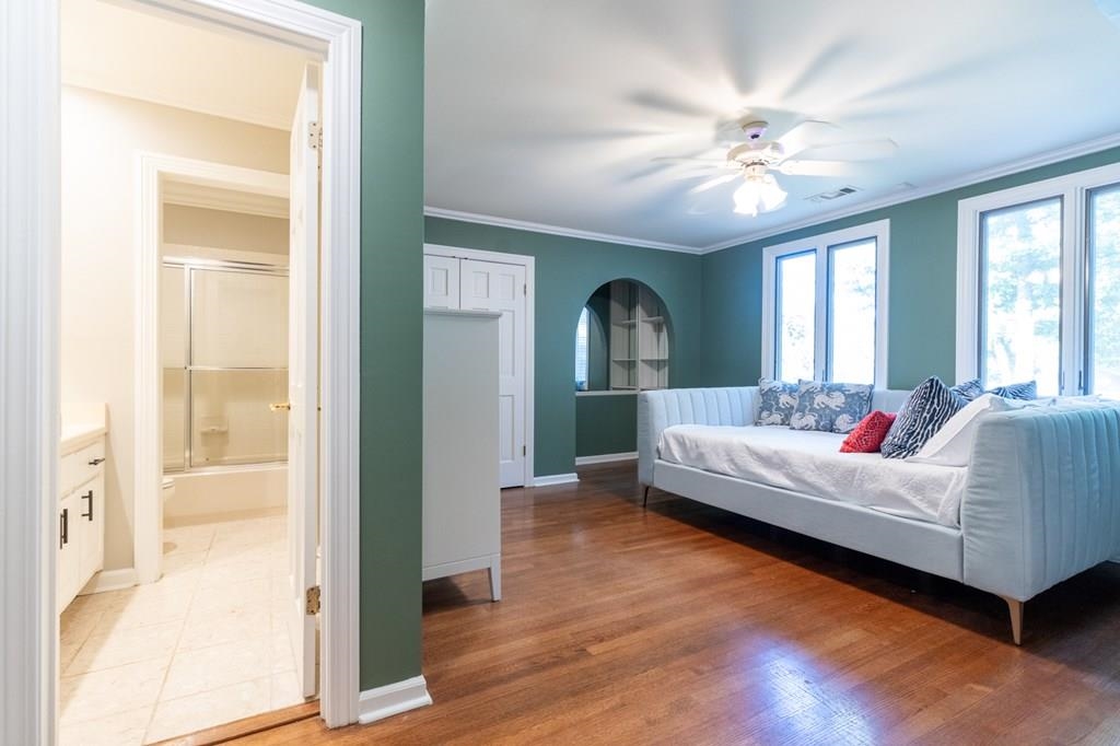Bedroom featuring ornamental molding, light hardwood / wood-style floors, ceiling fan, and ensuite bath