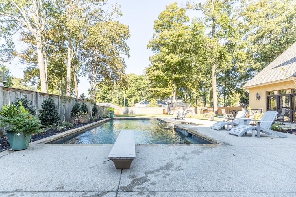 View of swimming pool featuring a diving board and a patio