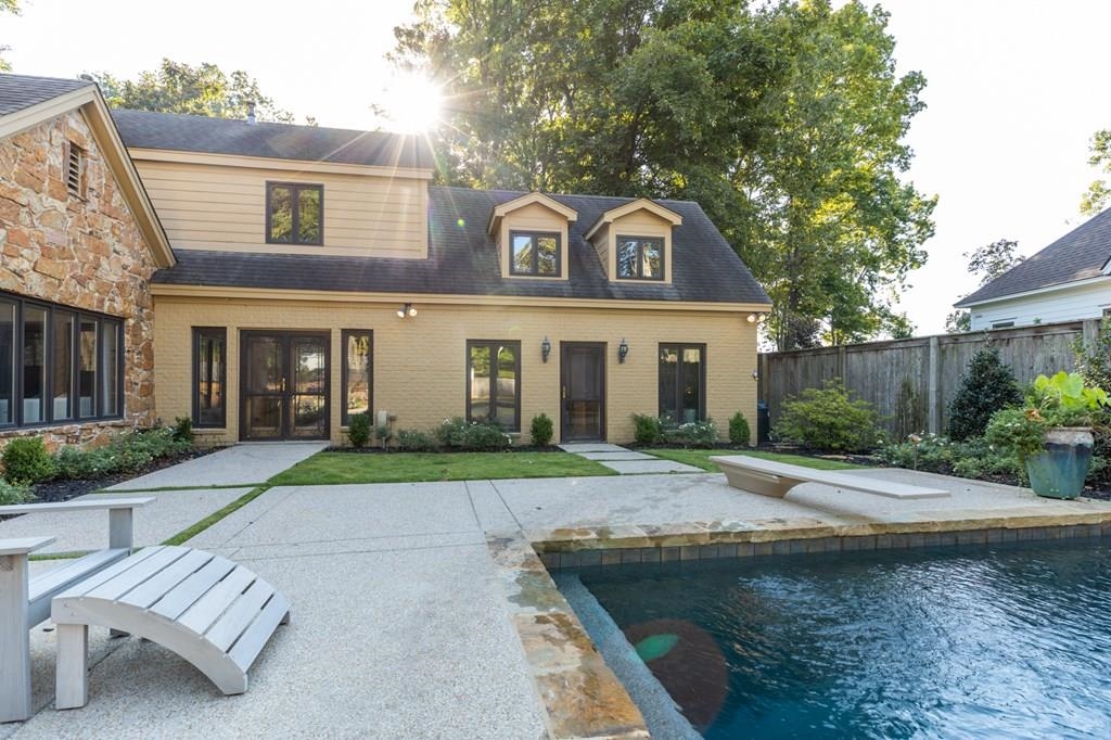 Back of property featuring a fenced in pool and a patio
