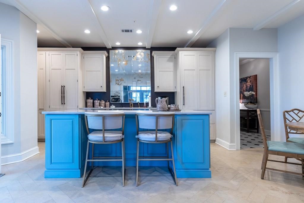 Kitchen featuring white cabinets, a kitchen breakfast bar, and a kitchen island