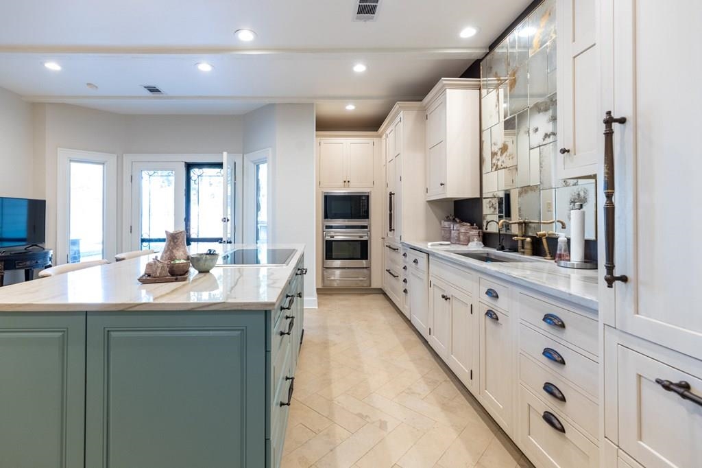 Kitchen featuring a kitchen island, white cabinetry, sink, and black electric stovetop