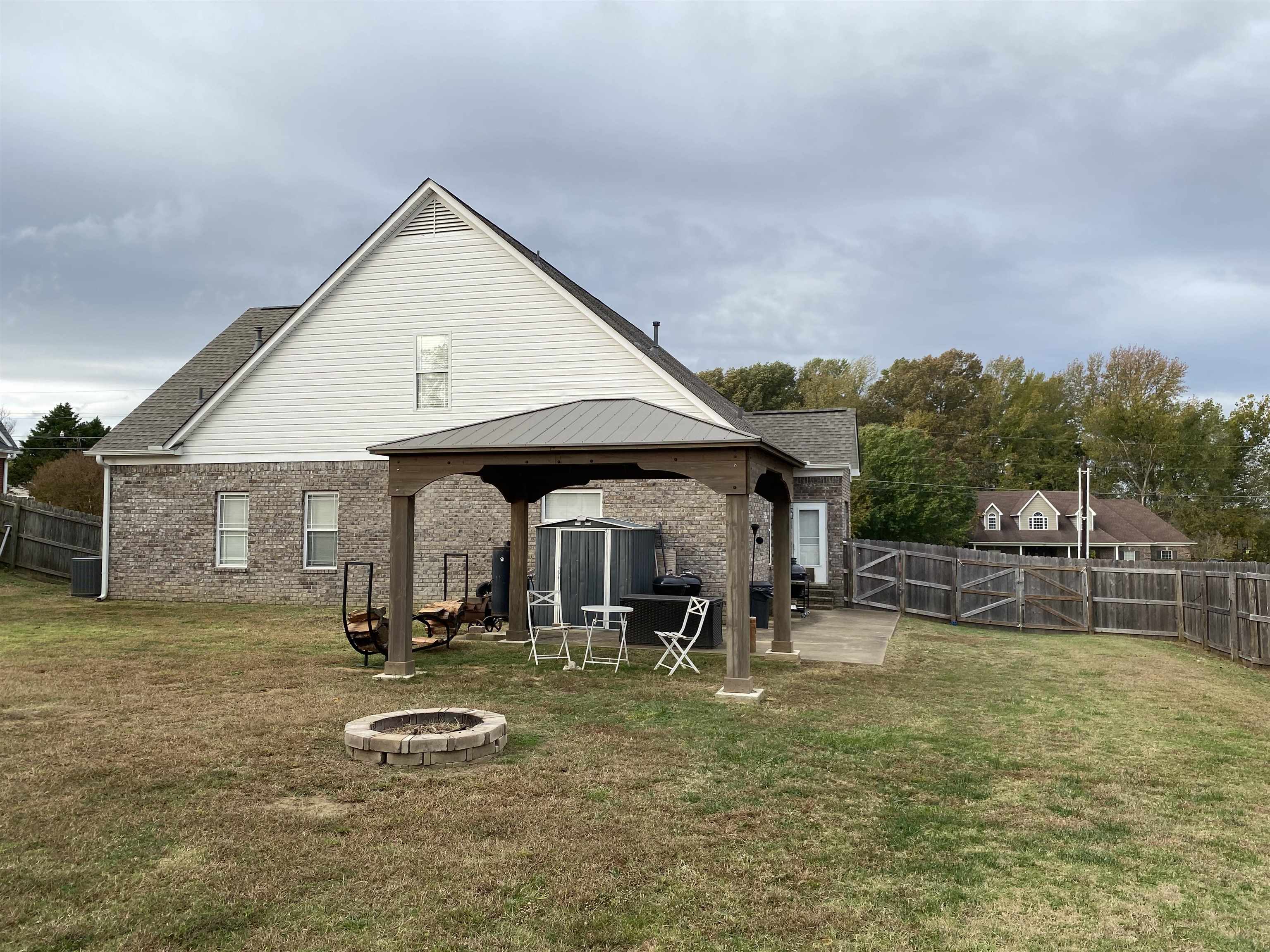 Rear view of property featuring central AC unit, an outdoor fire pit, a yard, and a gazebo