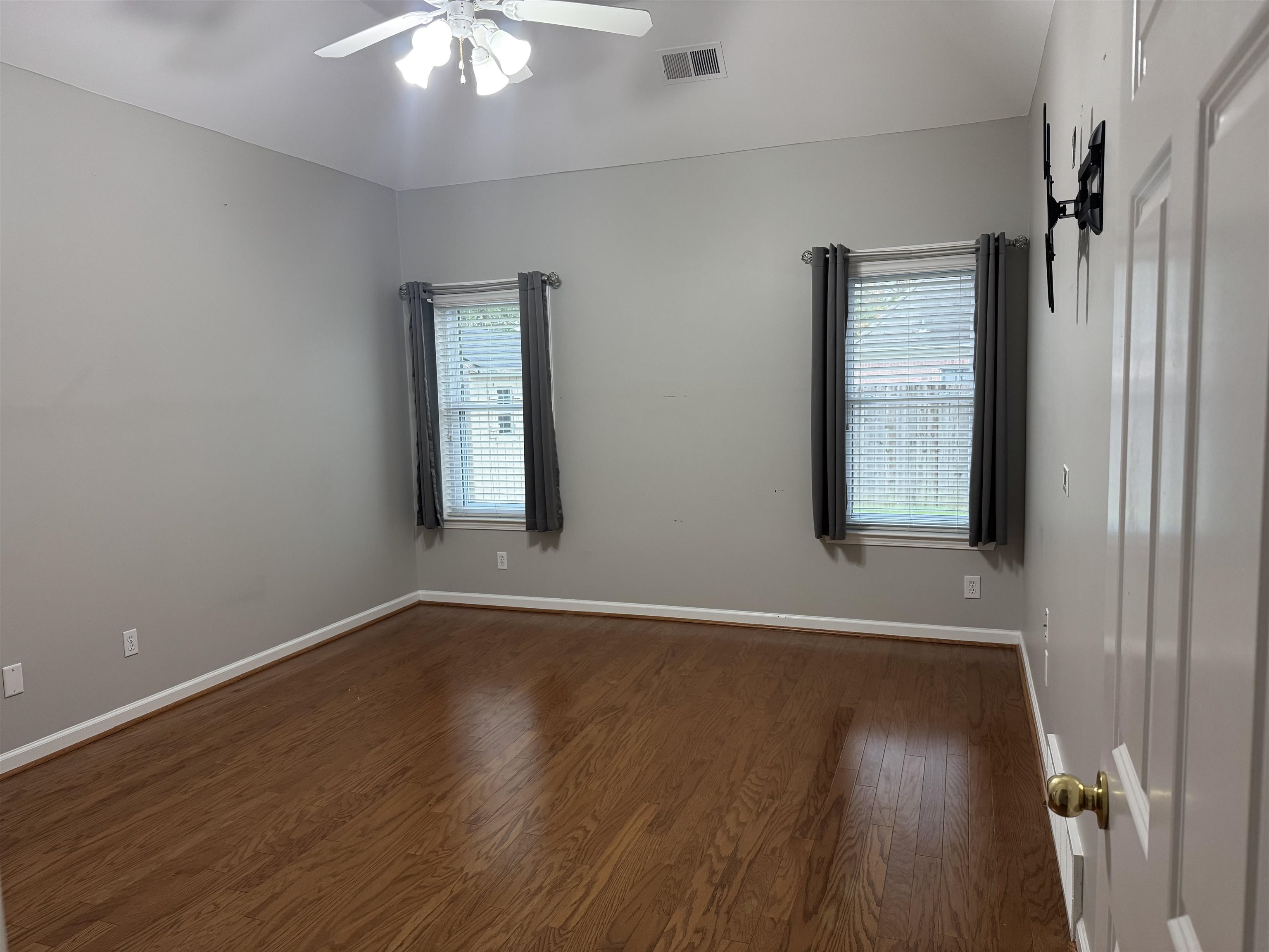 Empty room featuring ceiling fan and dark hardwood / wood-style floors