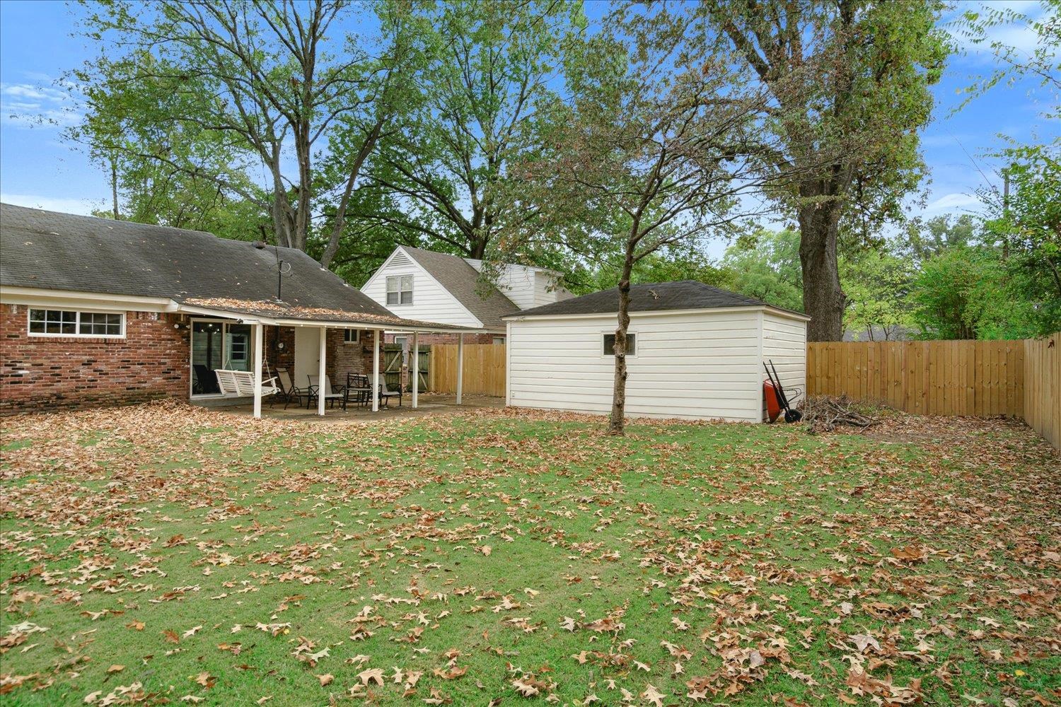 Rear view of house with a storage unit, a patio, and a yard